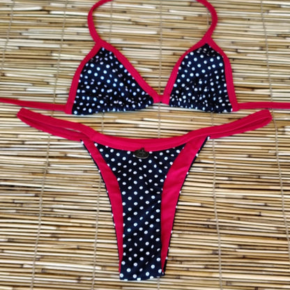 Black polka dot bikini with red straps on a woven mat